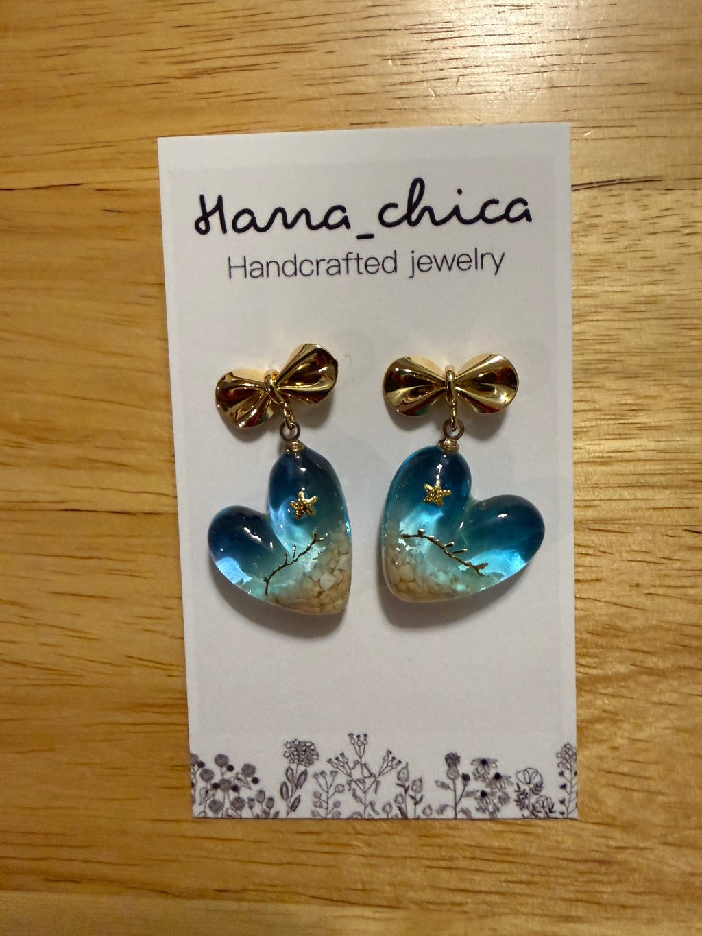Hana_chica handcrafted resin heart earrings with gold bow on white card