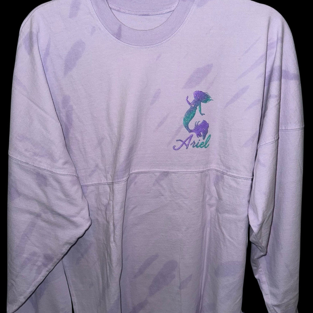 Marketplace239 LLC Disney Ariel Spirit Jersey in light purple tie-dye with a glittery Ariel silhouette on the chest.